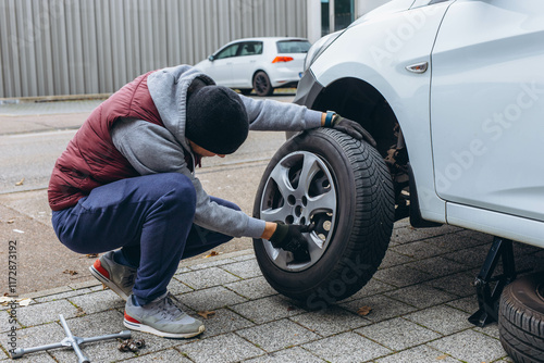 Εκτύπωση καμβά Man using a wrench to replace his car's tire, switching to winter tires for the