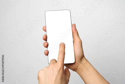 Finger touching phone on white background with copy space. Woman holding smartphone with white screen. Hand tap blank cellphone display, close-up