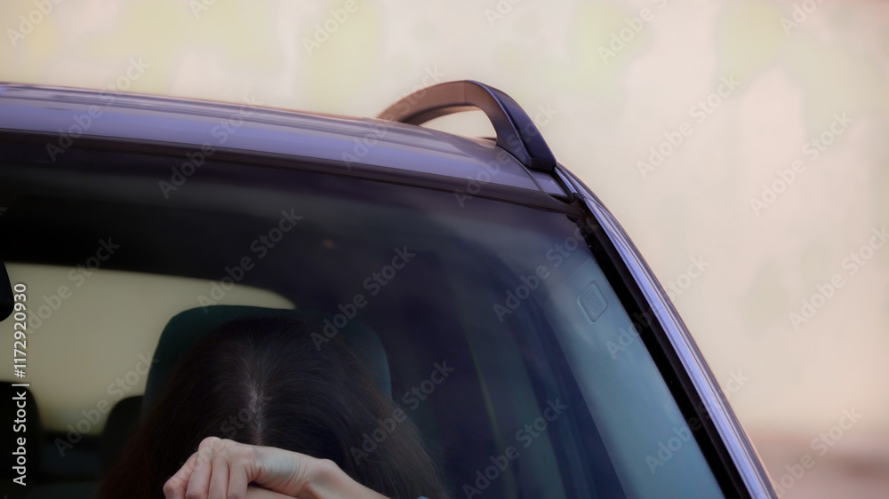 Tired young woman holding her head while driving car