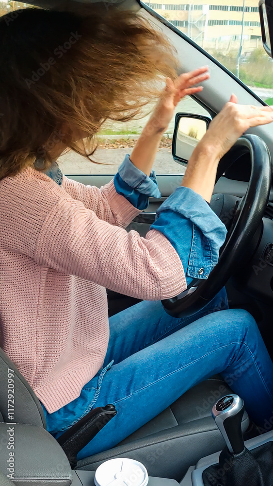 Frustrated young woman fixing her hair while driving a car