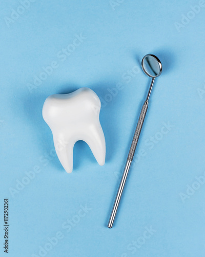 Vertical Mock-up healthy white tooth and dental mirror on blue background. For dental clinic, dentistry, healthcare, oral care. Oral hygiene, professional teeth cleaning. Copyspace for text