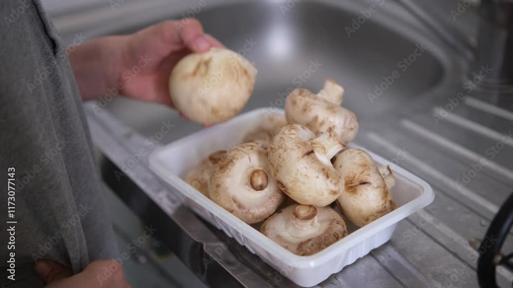 Washing mushrooms in the running water in the kitchen sink, slow motion. Little boy washes champignon mushrooms in a sink. Boy's hand washing mushroom with water sprinkling Washing mushrooms in the running water in the kitchen sink, slow motion. Little boy washes champignon mushrooms in a sink. Boy's hand washing mushroom with water sprinkling