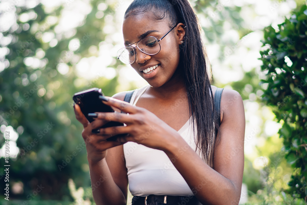 Smiling dark skinned woman making booking using 4g internet connection on smartphone sitting in park, beautiful cheerful hipster girl installing new application on mobile phone during free time Smiling dark skinned woman making booking using 4g internet connection on smartphone sitting in park, beautiful cheerful hipster girl installing new application on mobile phone during free time