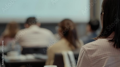 Rear view of seminar attendees sitting attentively in a conference room and a speaker presenting in front of a large screen. Seminar meeting, Business workshop concept