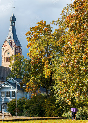 Autumn time in public park with a common view of old Lutheran church  built in 1909 with traits of national Latvian romanticism style. No AI tools were used  photo