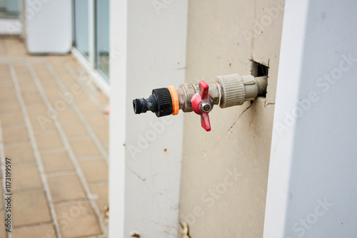 Building fire hydrants on the wall of a building. A water tap sticks out of the wall in the street. photo