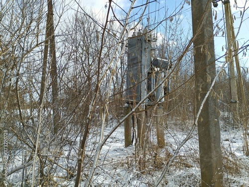 Electric gray transformer among bushes in a bush in winter. Electricity theme. photo