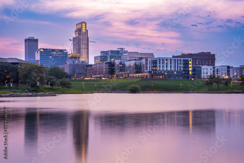 View of Omaha Nebraska skyline at sunset seen from Heartland of America Riverside Park with lake in view.