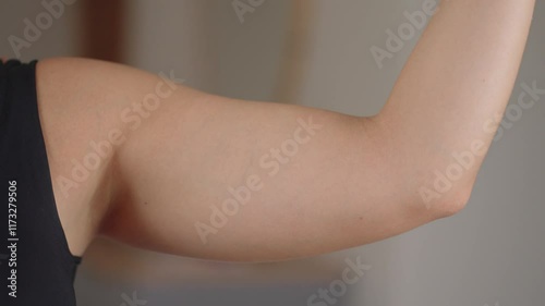 Close up shot of of a woman pinching the skin beneath her arm. Showing her fatty arm which needs to get reduced. No face
 photo