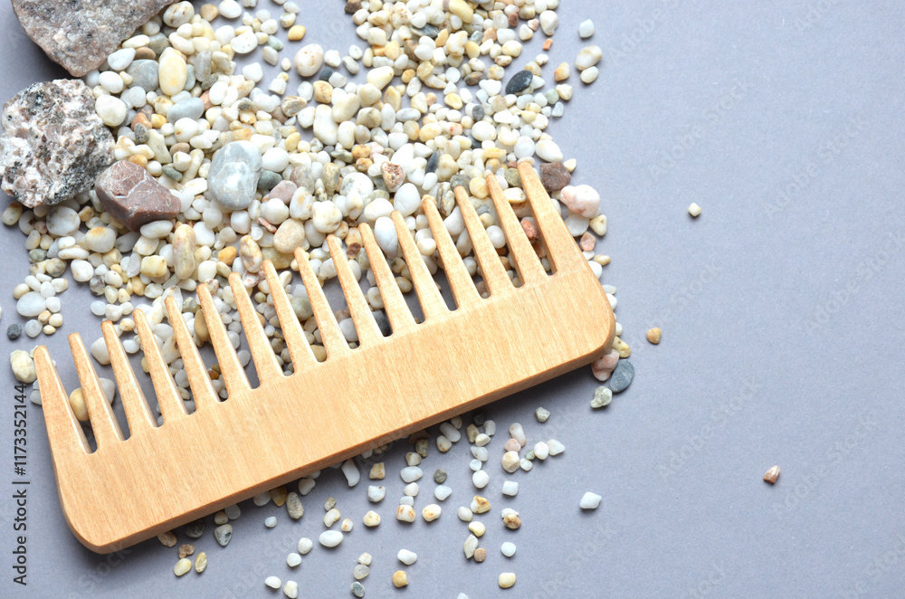 Wooden hair comb close-up. Many small and large stones on a gray background. Wooden hair comb close-up. Many small and large stones on a gray background.