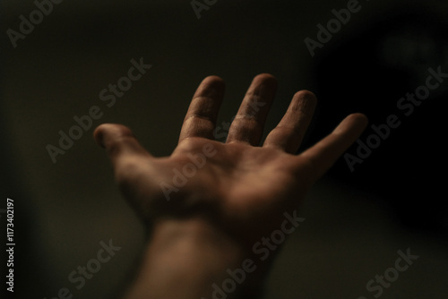Close-up personal perspective of an outstretched hand against a black background