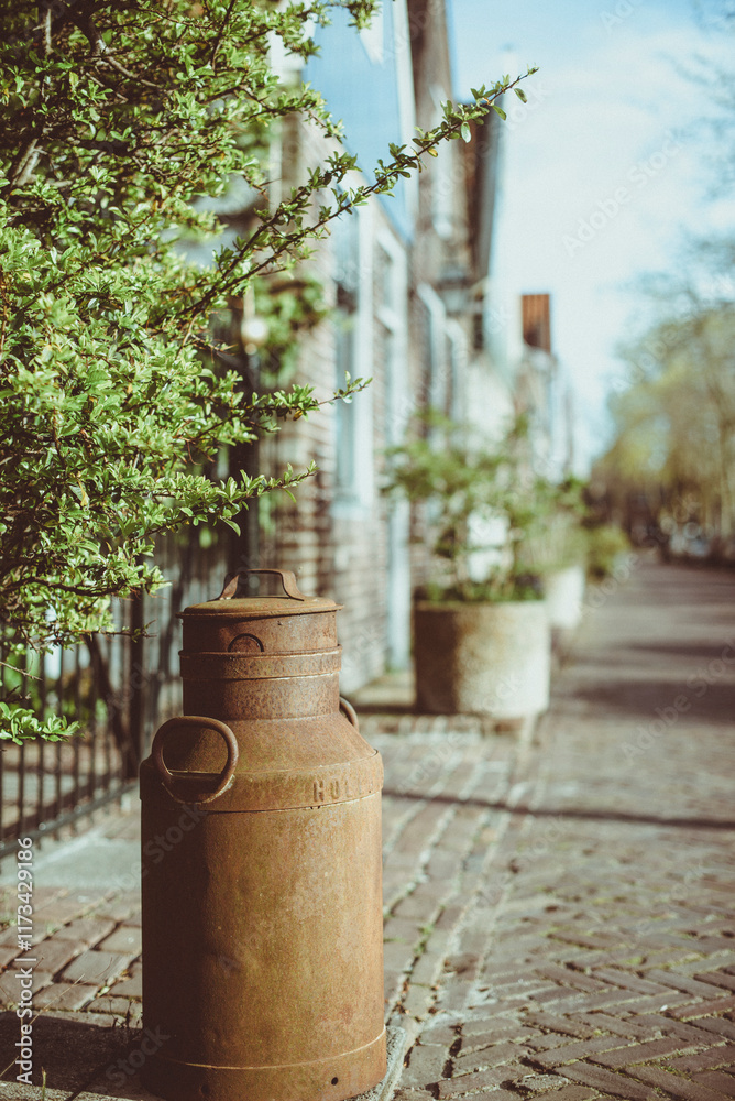 Traditional rusty metal milk churn in a cobbled street, Netherlands Traditional rusty metal milk churn in a cobbled street, Netherlands