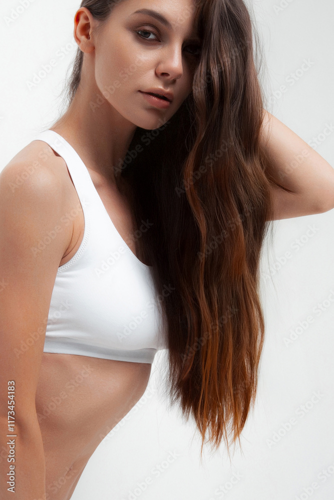 Young caucasian female with long brown hair in white tank top posing confidently Young caucasian female with long brown hair in white tank top posing confidently
