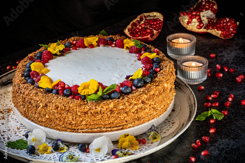 Medovik. Honey cake made from honey cakes with whipped sour cream, decorated with berries, pomegranate and flowers.