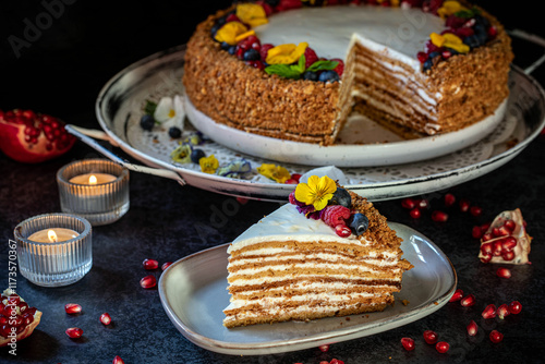 Medovik. Honey cake made from honey cakes with whipped sour cream, decorated with berries, pomegranate and flowers.