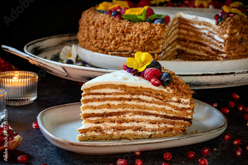 Medovik. Honey cake made from honey cakes with whipped sour cream, decorated with berries, pomegranate and flowers. photo