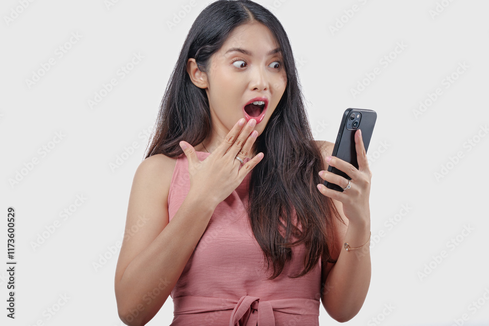 Shocked young Asian woman holding a smartphone with a surprised expression on her face. Shocked young Asian woman holding a smartphone with a surprised expression on her face.