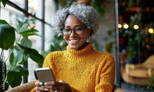 Older African-American woman smiling while sitting in living room using smartphone, slow motion