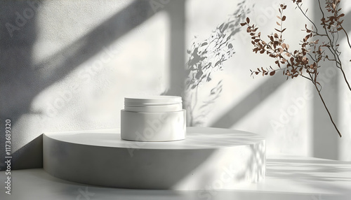 White jar on a minimalist white platform against a textured white wall with shadows and dried flowers.
