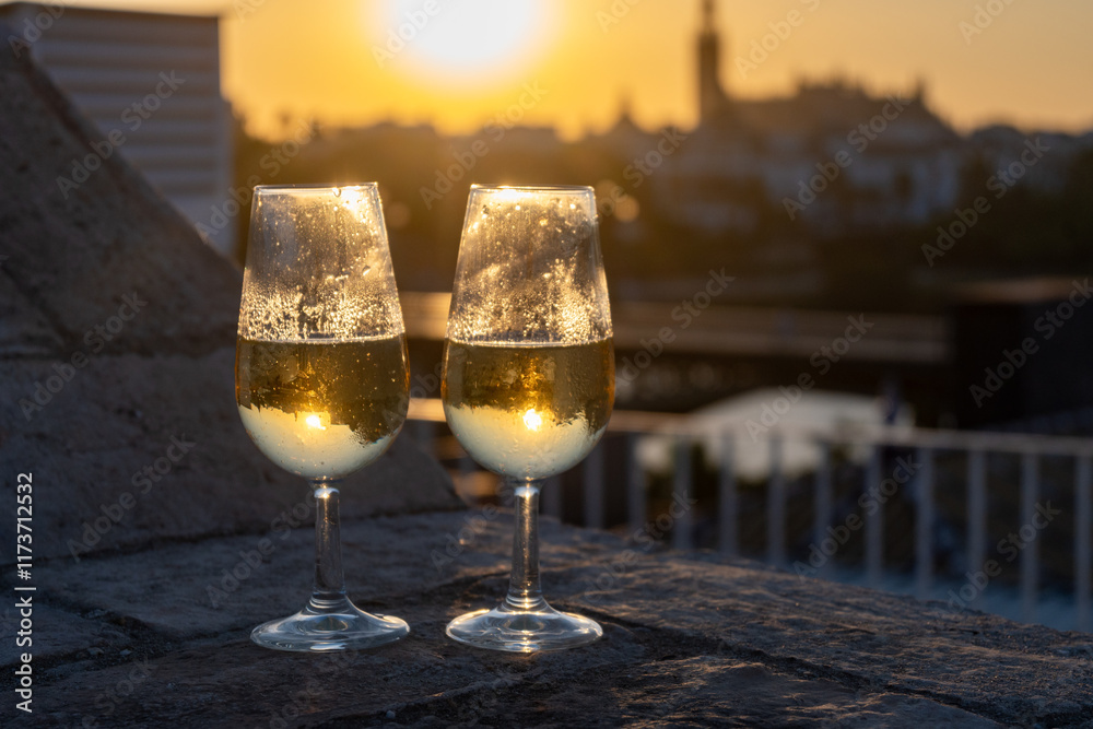 Fototapeta premium Drinking of cava or champagne sparkling wine on outdoor roof terrace with view on central part of old Sevilla, Andalusia, Spain sunset