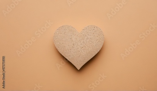 A simple, yet elegant heart shape cut from a warm-toned paper, resting on a complementary background.