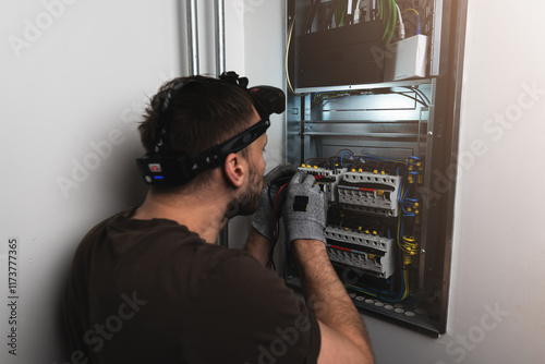 An electrician carefully checks an electrical panel, using a multimeter to measure voltage and ensure safe functionality