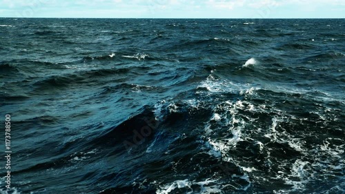 Storm, sea. Wind breaks waves with splashes. White foam on wind. Side view along ship.