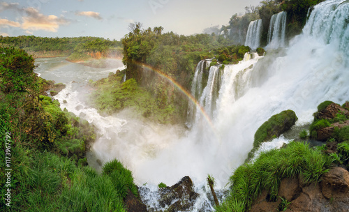Obraz na płótnie Majestic Iguazu Falls on the Argentine side, with cascading waterfalls surrounded by lush greenery and a misty rainbow arching through the scene w salonie