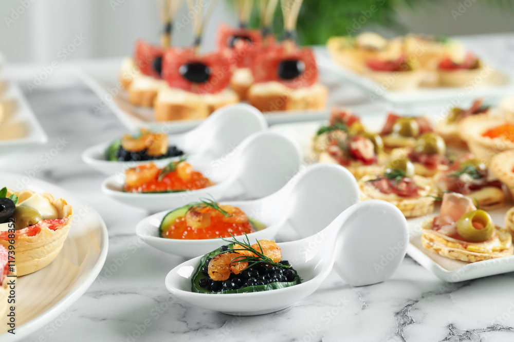 Many different tasty canapes on white marble table, closeup Many different tasty canapes on white marble table, closeup
