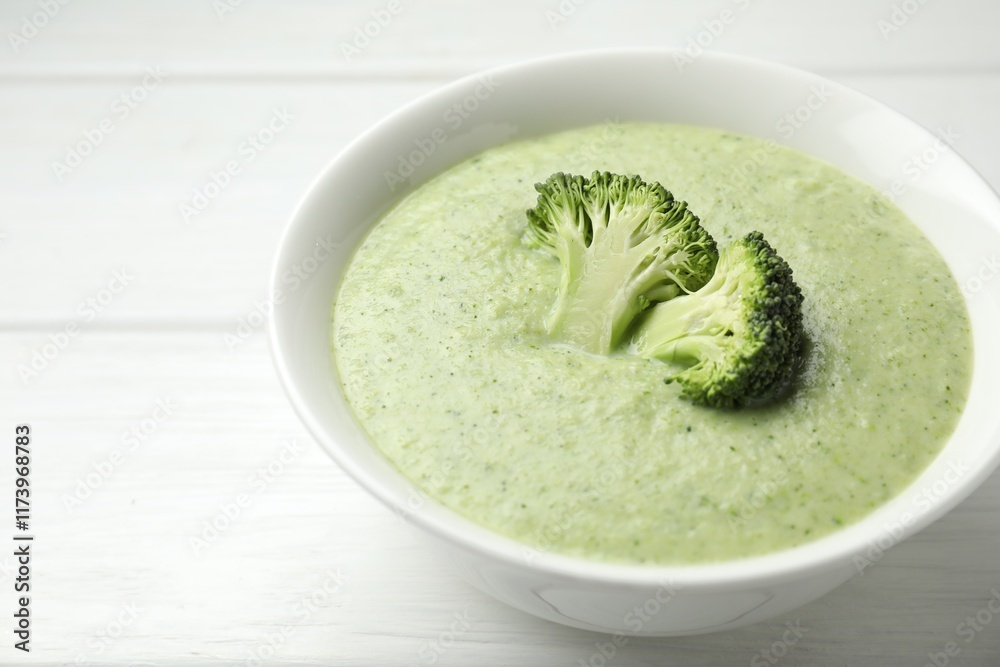 Delicious broccoli cream soup in bowl on white wooden table, closeup Delicious broccoli cream soup in bowl on white wooden table, closeup