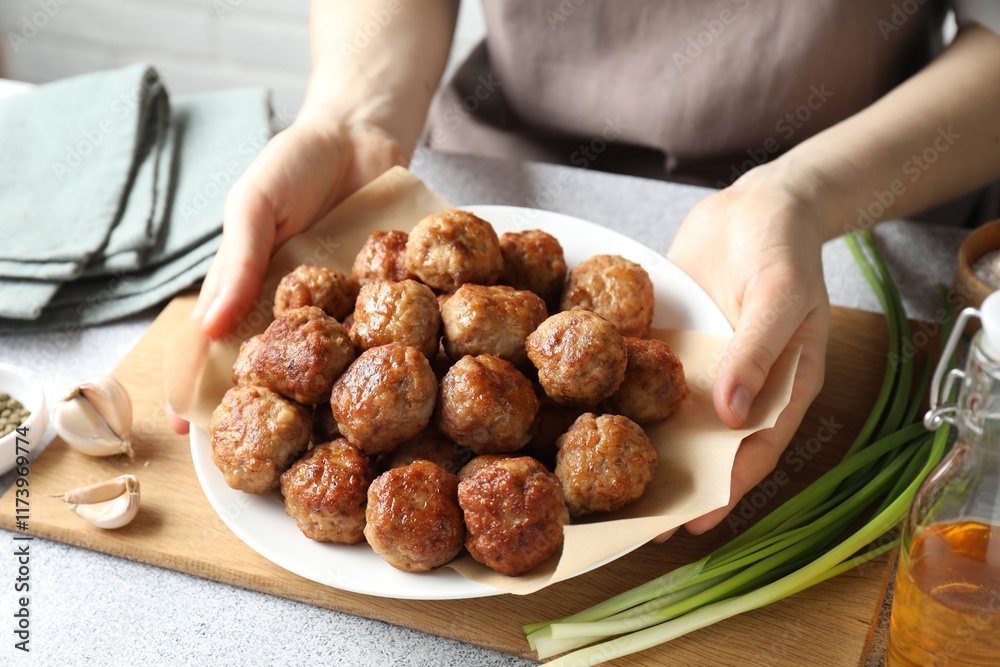 Woman holding plate with delicious meatballs at light textured table, closeup Woman holding plate with delicious meatballs at light textured table, closeup