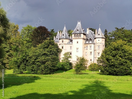 Photo showing the castle in Gołuchów in Poland at sunset, in summer, surrounded by a park.
