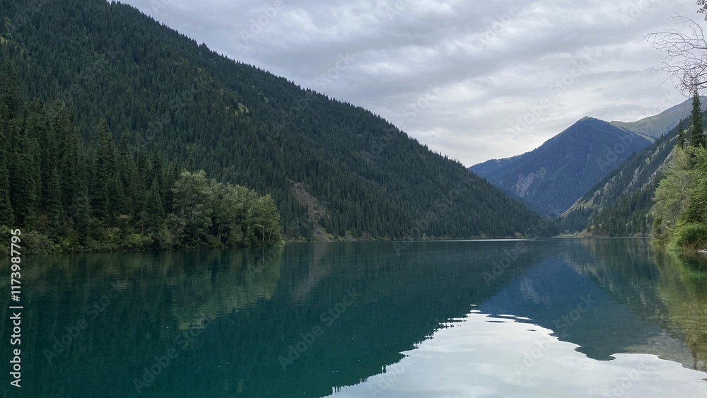 Mountains with pine trees are reflected in the calm surface of the water. Mountains with pine trees are reflected in the calm surface of the water.