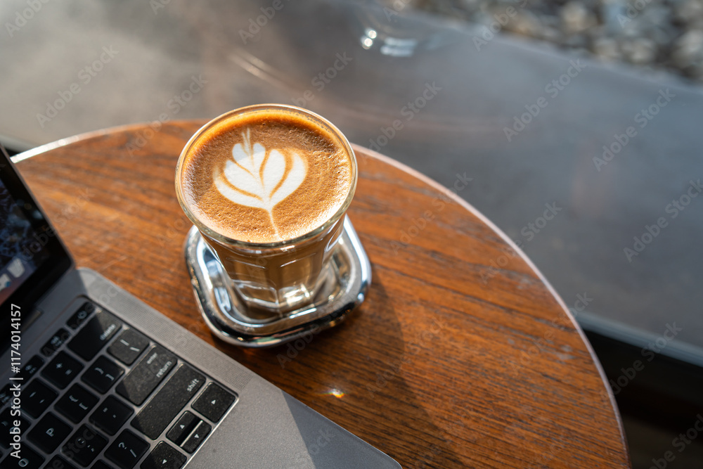Close-up of Hot coffee latte with latte art milk foam in cup mug and laptop computer on wood desk office desk in coffee shop at the cafe,during business work concept