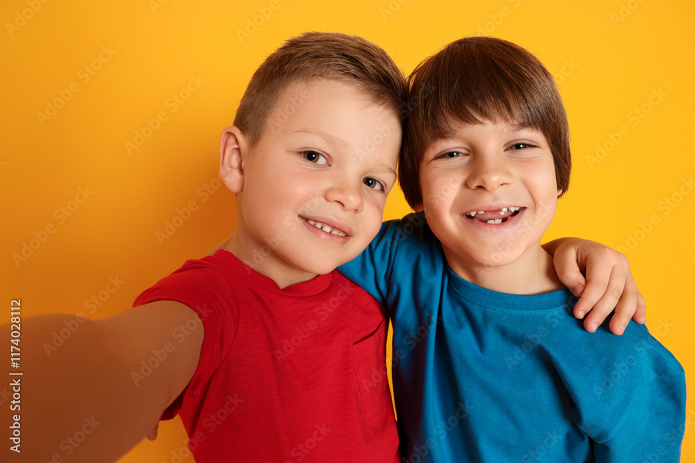 Cute brothers taking selfie on orange background Cute brothers taking selfie on orange background