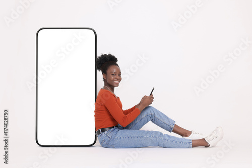 Foto Happy woman with smartphone leaning on big mobile phone with blank screen on whi