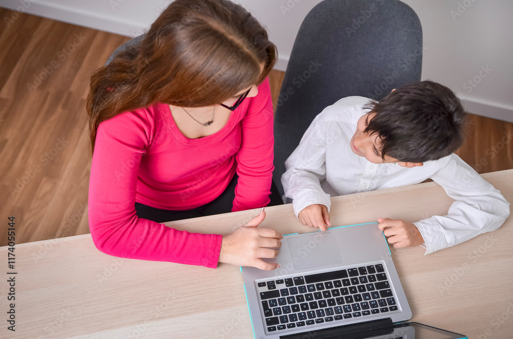 Teacher helping young student using laptop in class Teacher helping young student using laptop in class