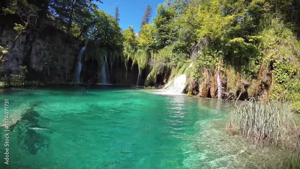Crystal-clear turquoise water with cascading waterfalls surrounded by lush greenery in a serene natural setting, perfect for relaxation and nature lovers