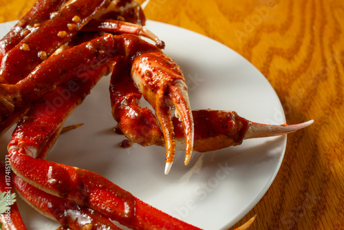 A closeup view of snow crab legs and claws, topped with spicy garlic cajun sauce. photo