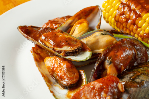 A view of a plate of steamed green mussels, topped with spicy cajun sauce.