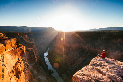 Man on the edge of the Grand Canyon at sunrise, Arizona, United States