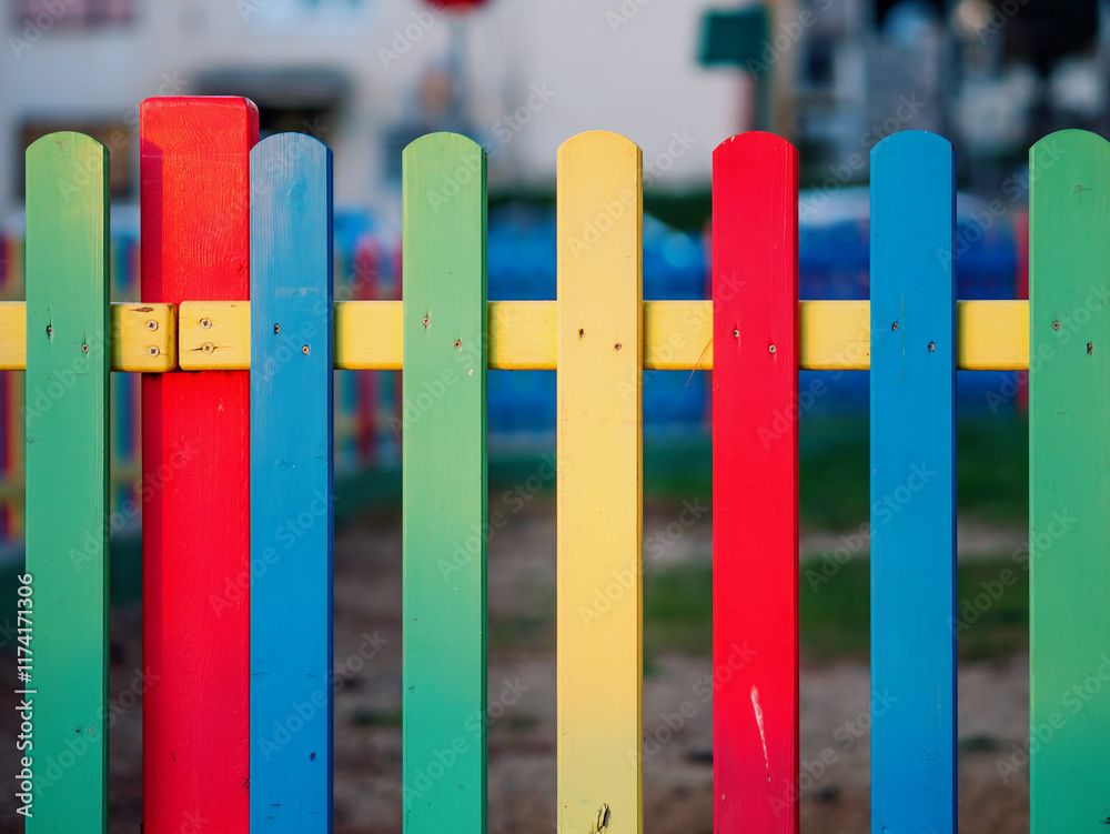 The colorful painted wooden boards on the fence around a playground are illuminated by the rays of the setting sun. Pula, Croatia - January 3, 2025 The colorful painted wooden boards on the fence around a playground are illuminated by the rays of the setting sun. Pula, Croatia - January 3, 2025