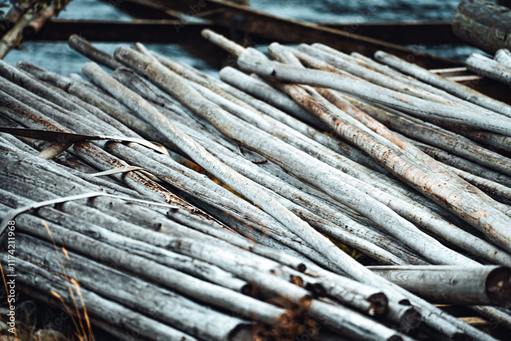 A collection of weathered wood sticks is thoughtfully arranged and piled up by the shoreline A collection of weathered wood sticks is thoughtfully arranged and piled up by the shoreline