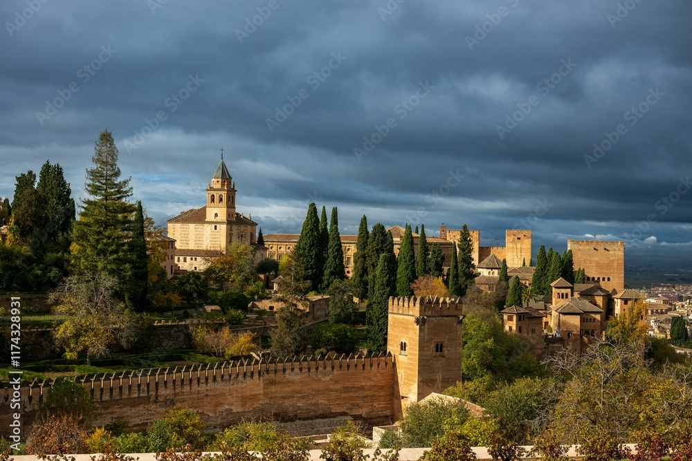 Obraz premium A view of the Alhambra in Granada, Spain, with dramatic clouds and lush greenery.