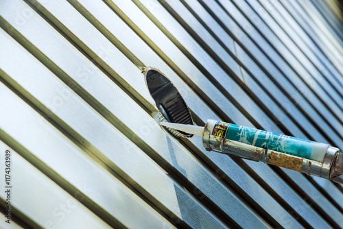 Construction worker applies caulk to pvc siding using caulking gun on ensuring secure weather proof finish. photo