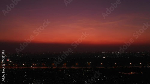 view of sunset city skyline, transportation with cars on Expressway, Road, Roundabout, multilevel junction highway-Top view. Important infrastructure, cloudscape, cityscape, building, crane.