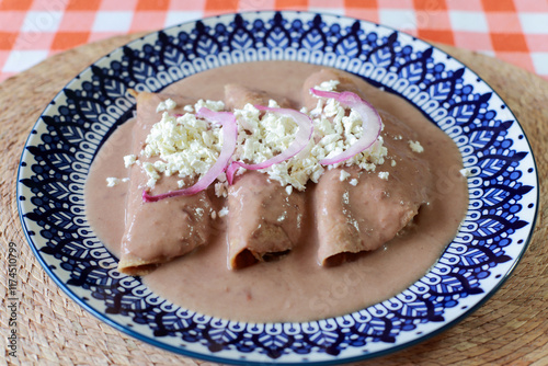 Enfrijoladas, chicken wrapped in tortillas with bean sauce, cream and cheese