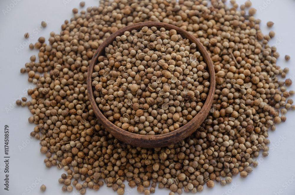 Whole coriander grain in a wooden plate and scattered around the edges Whole coriander grain in a wooden plate and scattered around the edges