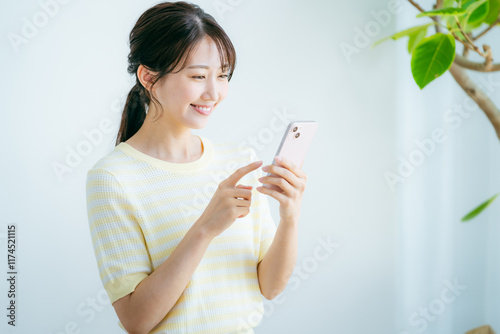 部屋でスマホを操作する女性