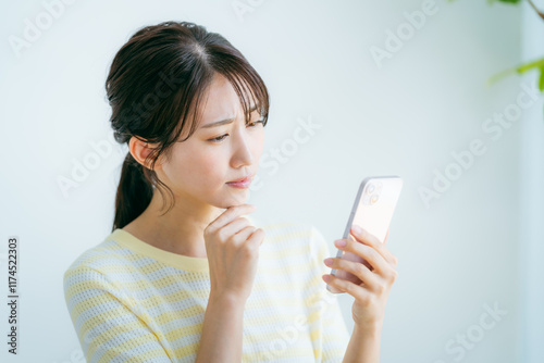 部屋でスマホを操作する女性